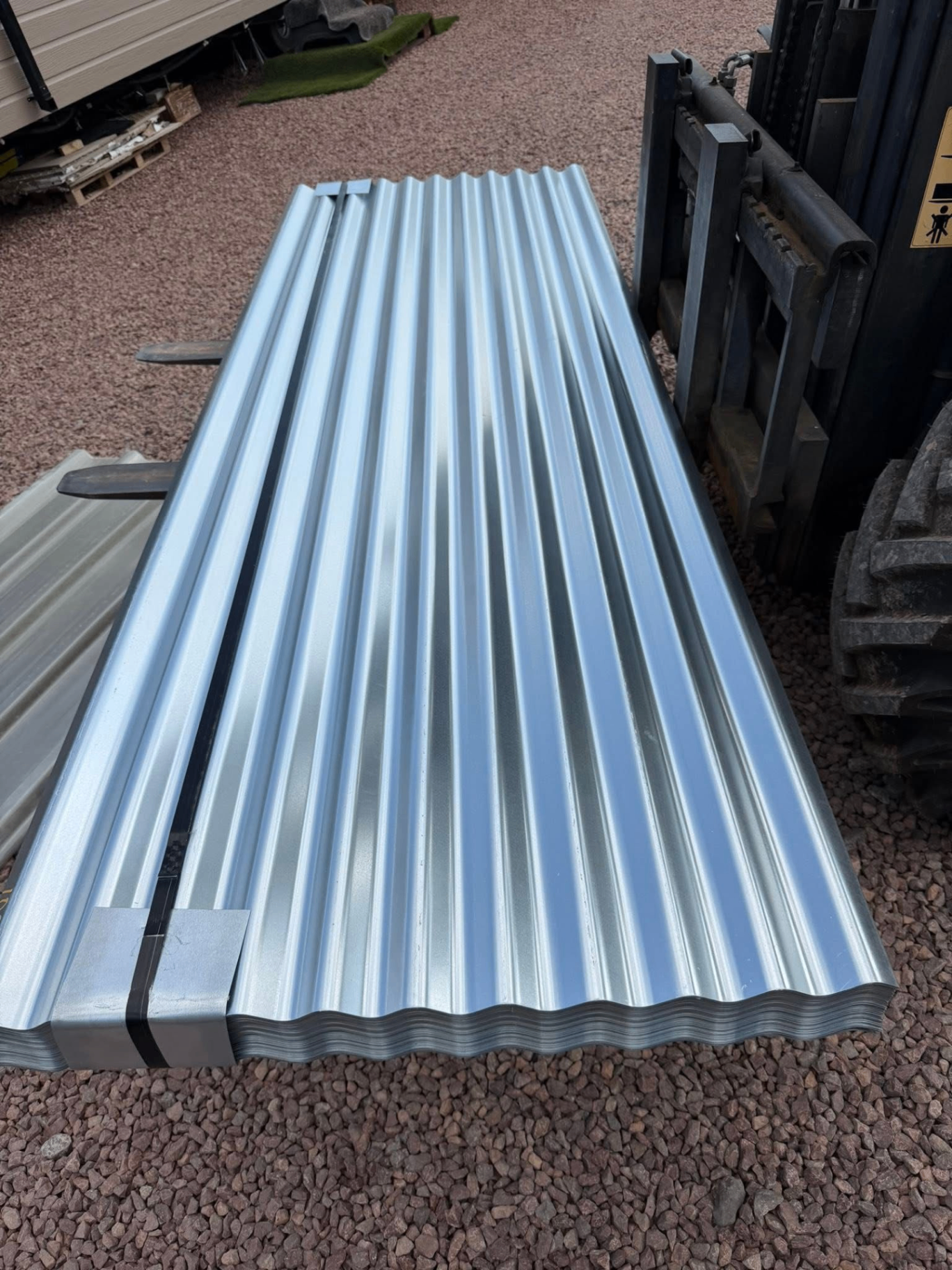 Galvanised corrugated roofing sheets stacked on forklift
